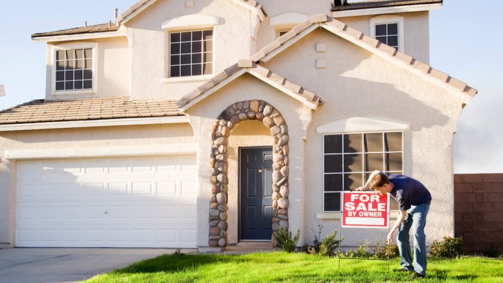 man putting down sign in front of home