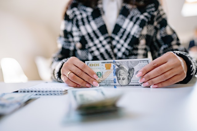 half body shot of a woman holding 100 dollar bill over a table