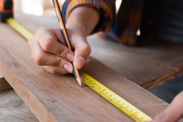 Hand measuring a board in order to cut 