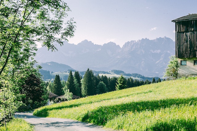 land with a dirt road and a house in the corner