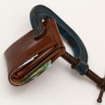 Wallet being squeezed by a rusted clamp .Easy Guide to Alabama Real Estate Taxes.