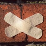two elastoplasts on a red brick wall. Tips on How to Sell a Damaged House in Alabama.