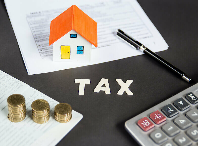 Pen, model house, some coins and calculator to calculate capital gains tax Louisville