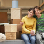 smiling young couple sitting back of moving van