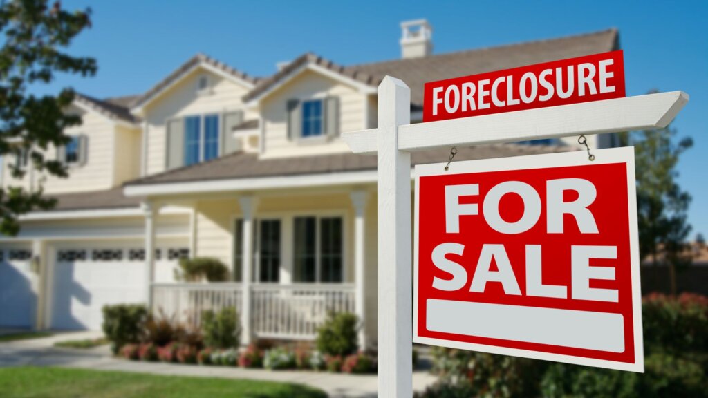 A signboard that says "For Sale" with a house in the background