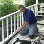 Owner on his knees repairing a weathered front porch.