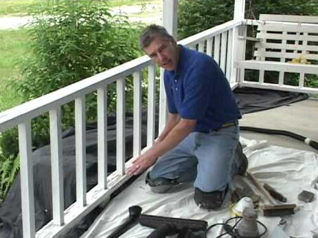 Owner on his knees repairing a weathered front porch.