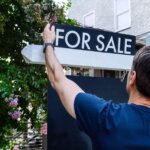 a guy installing a for sale signage in front of the house