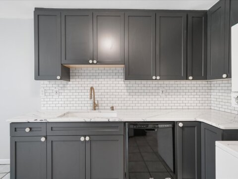 updated kitchen with Gray color cabinets, white subway backsplash, white with gray and black lined quartz countertop, gold faucet, white quartz sink