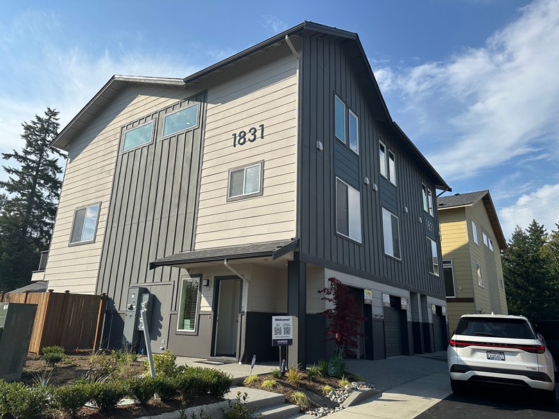 Modern townhomes in Everett, WA with large windows, gray siding, and individual garages, showcasing clean architectural lines and a newly built neighborhood