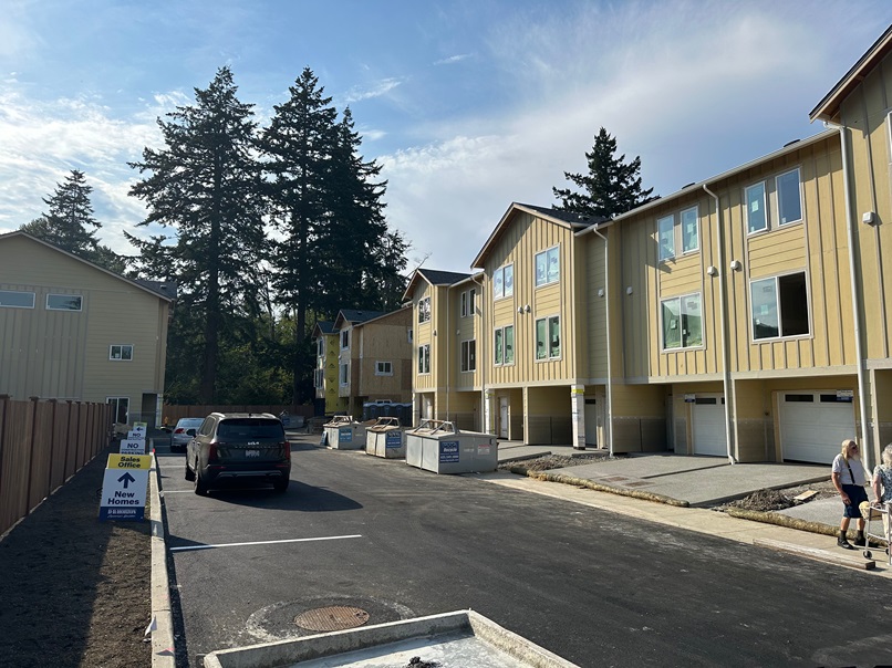 Newly developed townhome community in Everett, WA with yellow and gray exteriors, freshly paved road, and landscaped surroundings