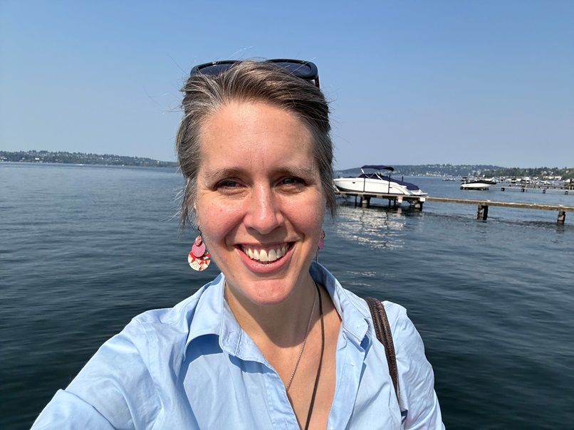 The Seattle skyline is faintly visible across the lake, and lush green trees line the shore. It’s a perfect snapshot of Kirkland’s vibrant yet peaceful atmosphere.