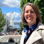 Emily Cressey strolling around the heart of Seattle, overlooking the Seattle Great Wheel, navigating the busy street in Downtown Seattle