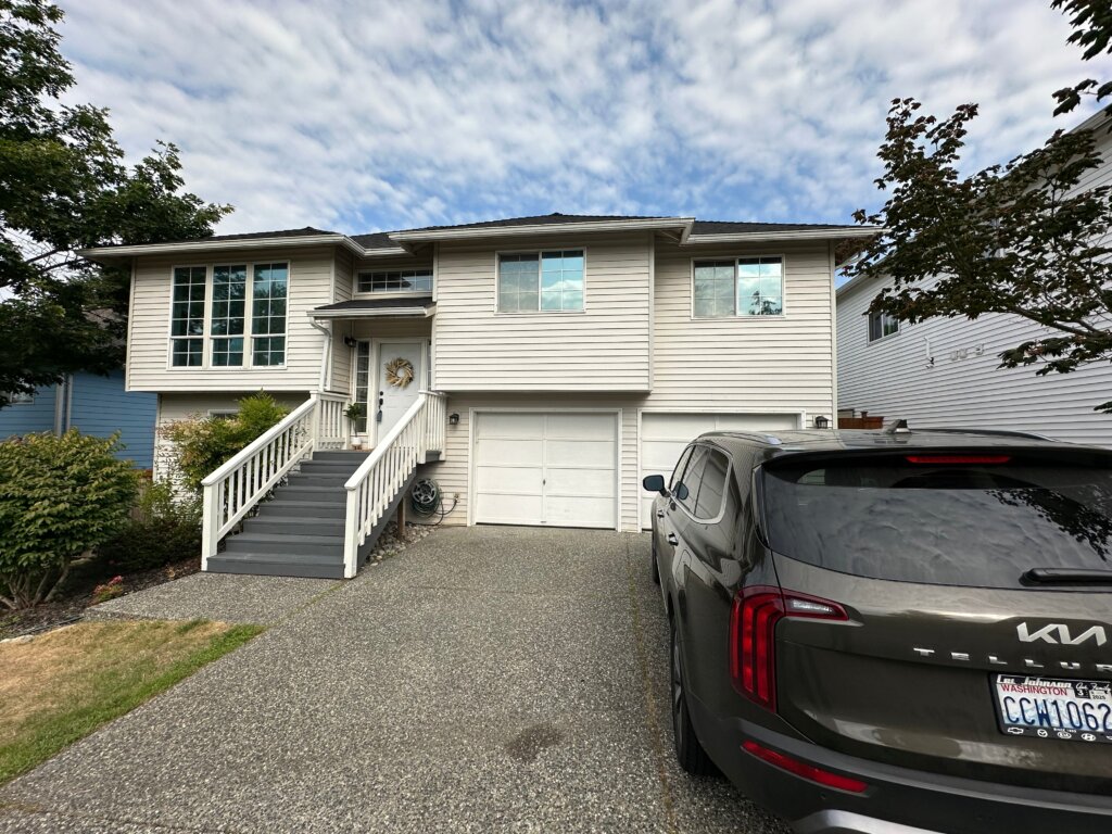 Contemporary white split-level home in Tacoma with an inviting staircase, two-car garage, and spacious driveway