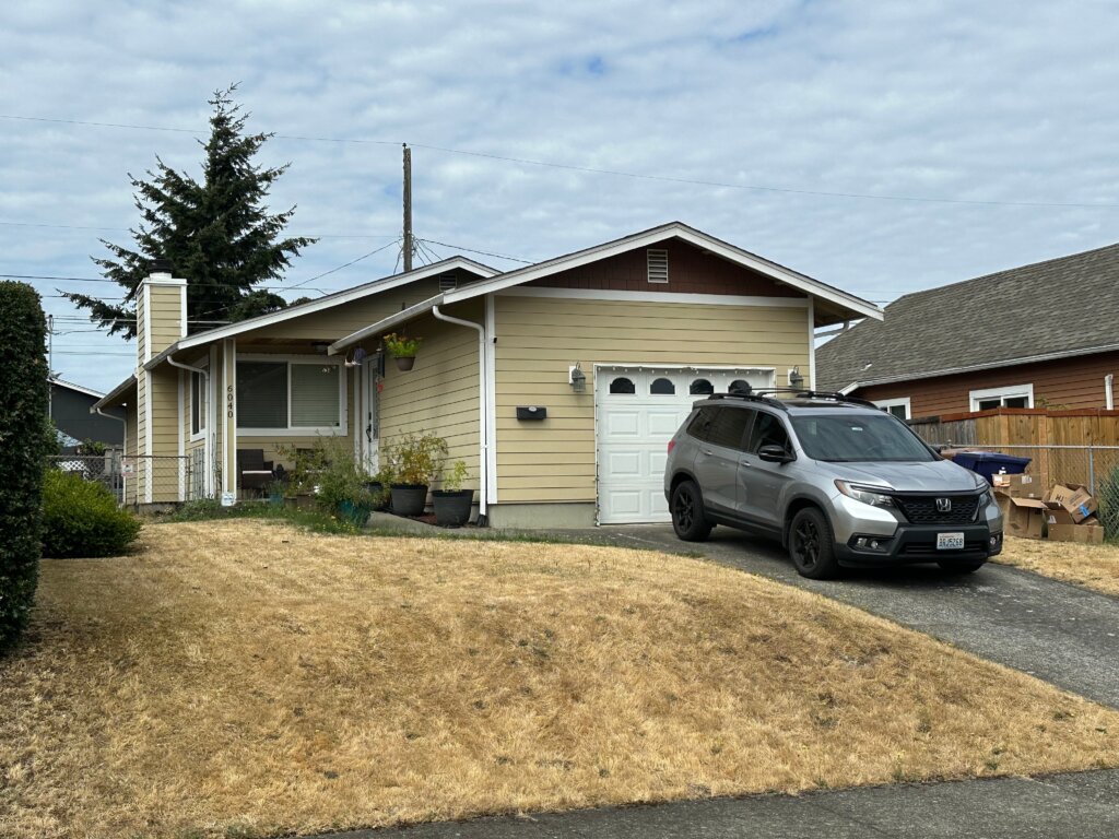 Cozy yellow ranch-style home in Tacoma with a welcoming front porch and well-maintained driveway.