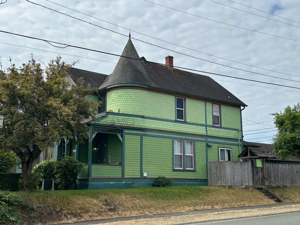 Green Victorian-style house in Tacoma with turret and intricate trim details.