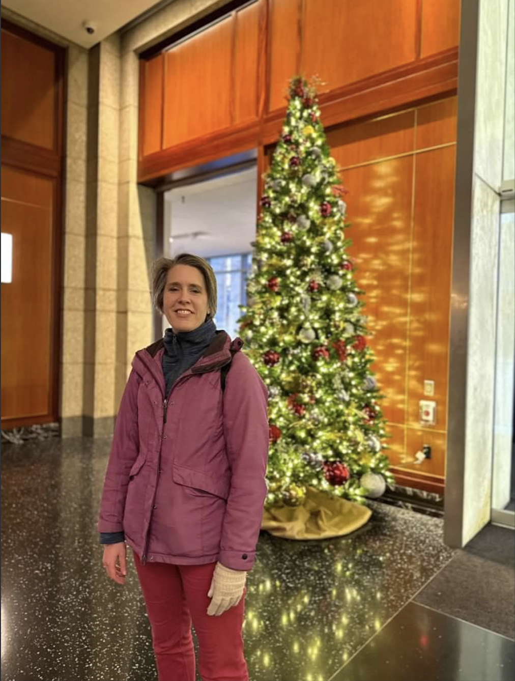 Emily Cressey celebrating Christmas beside a decorated Christmas tree
