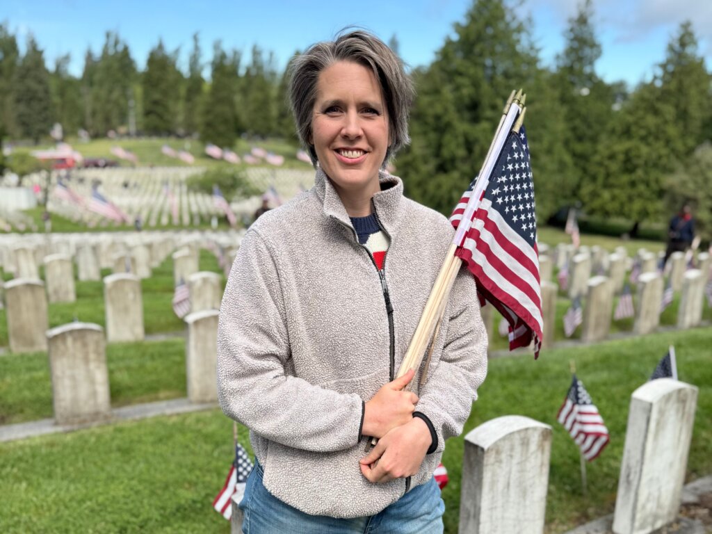 Emily Cressey holding an American flag at a military cemetery