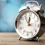 an old school chrome alarm clock pointing to 11:54