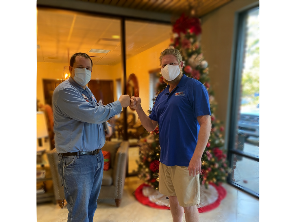 Photograph of Greg and Jake fist bumping and wearing face masks
