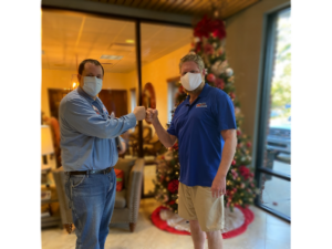 Photograph of Greg and Jake fist bumping while wearing protective face masks