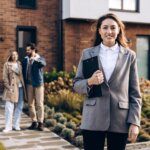 Realtor standing outside a Greensboro home with sellers, comparing a cash offer to listing