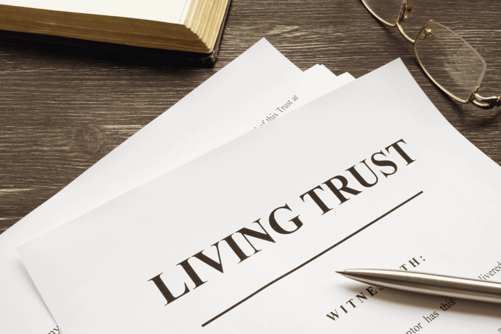 Close-up of a document titled “Living Trust” on a wooden desk with a pen and reading glasses.