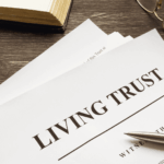 Close-up of a document titled “Living Trust” on a wooden desk with a pen and reading glasses.