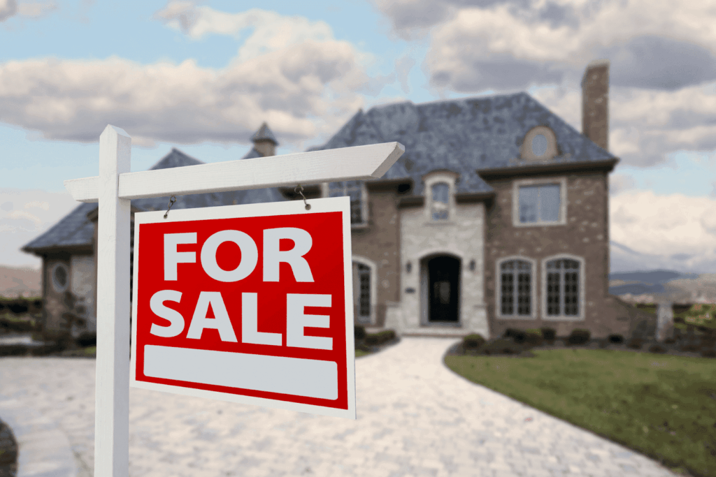 For Sale sign in front of a large brick house.