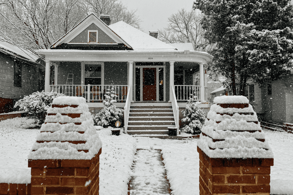 Front view of a house covered in snow during winter with snow falling.