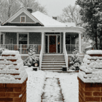 Front view of a house covered in snow during winter with snow falling.