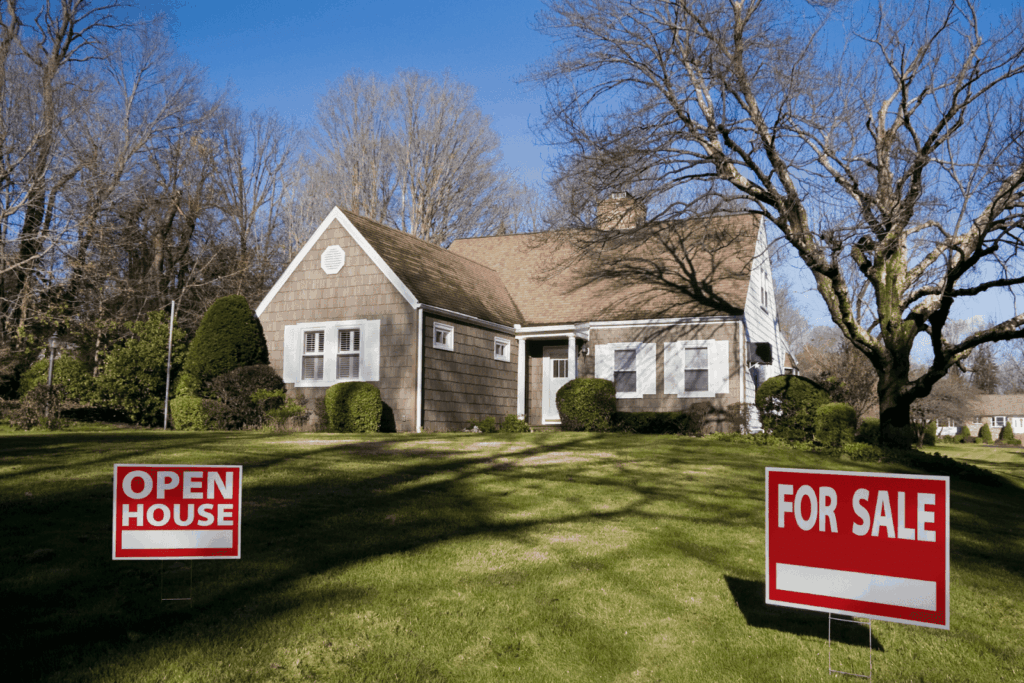 House with open house and for sale signs on front lawn.