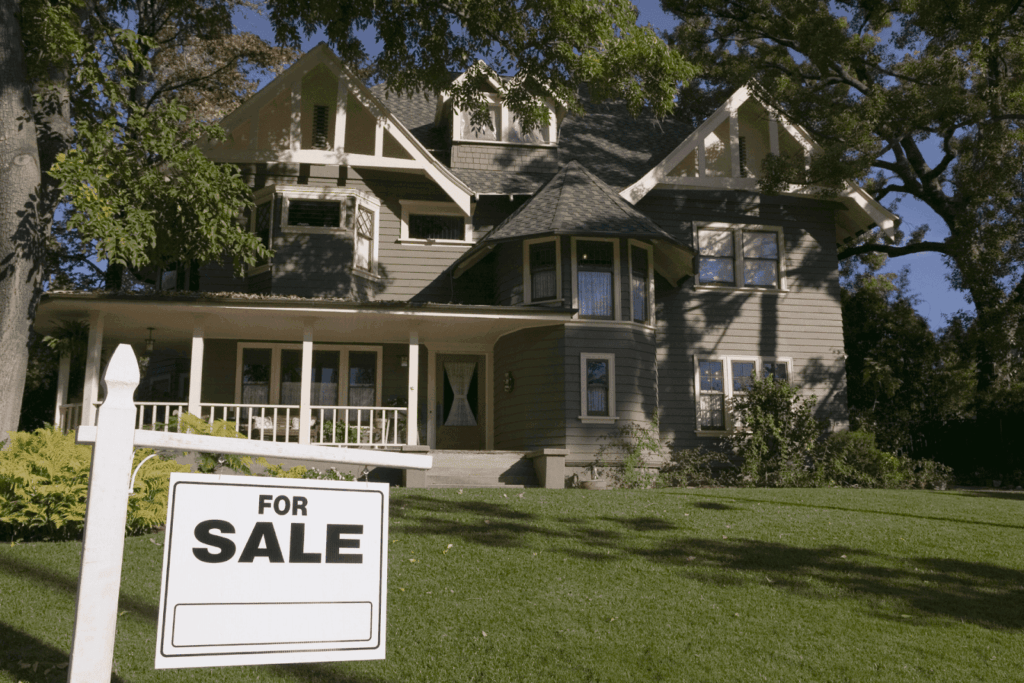 Large house with a for sale sign in the front yard.