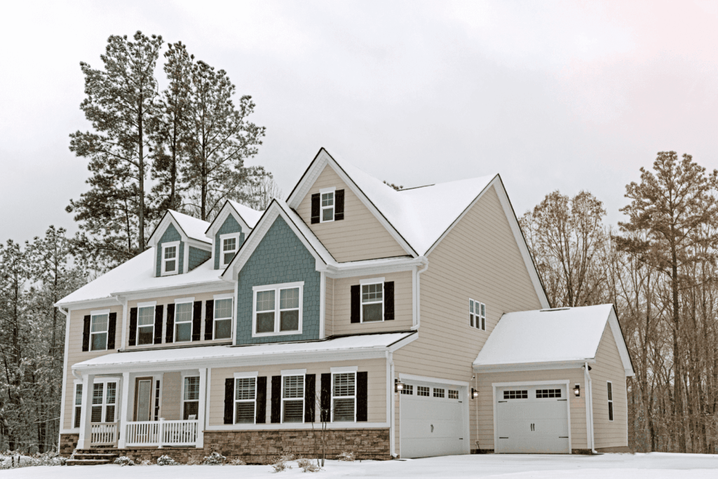 Large two-story house with blue and beige siding covered in snow.