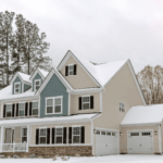 Large two-story house with blue and beige siding covered in snow.