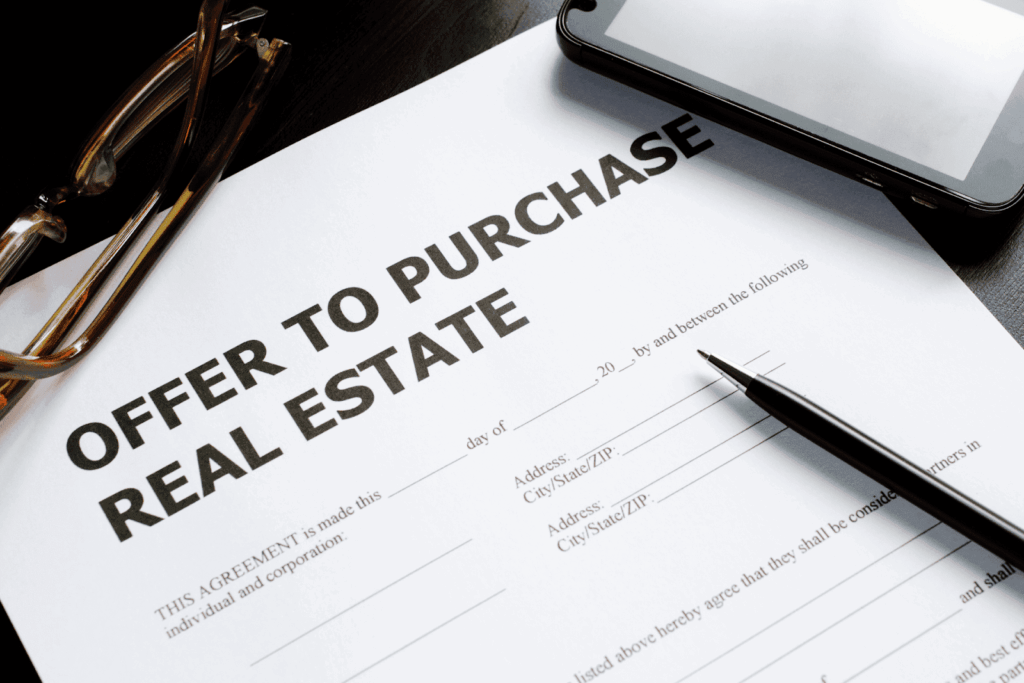 Offer to purchase real estate document with pen, glasses, and phone on desk.
