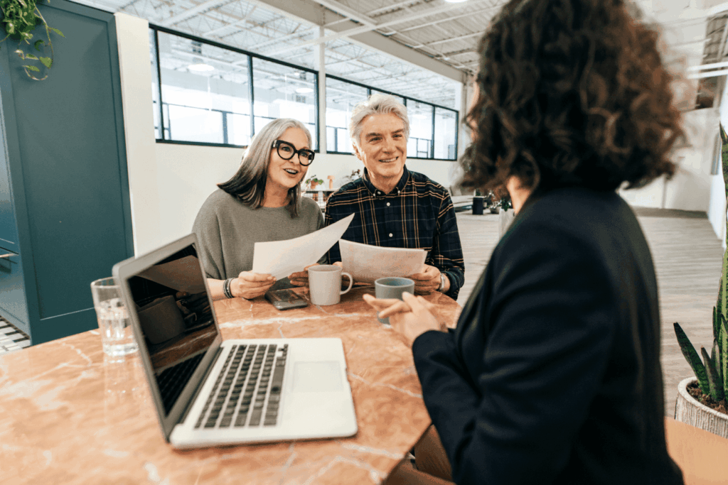 Older couple meeting with advisor at table holding paperwork.