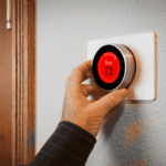 Person adjusting a smart thermostat set to 72 degrees for heating.