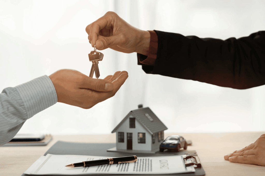 Person handing over house keys during a real estate transaction.