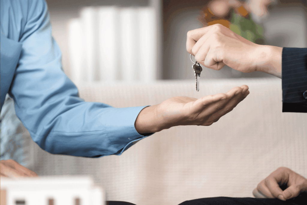 Person handing over house keys to another person indoors