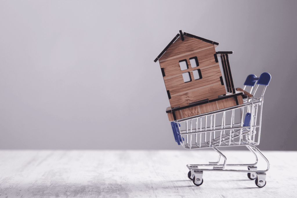 Small wooden house model inside a shopping cart on a table