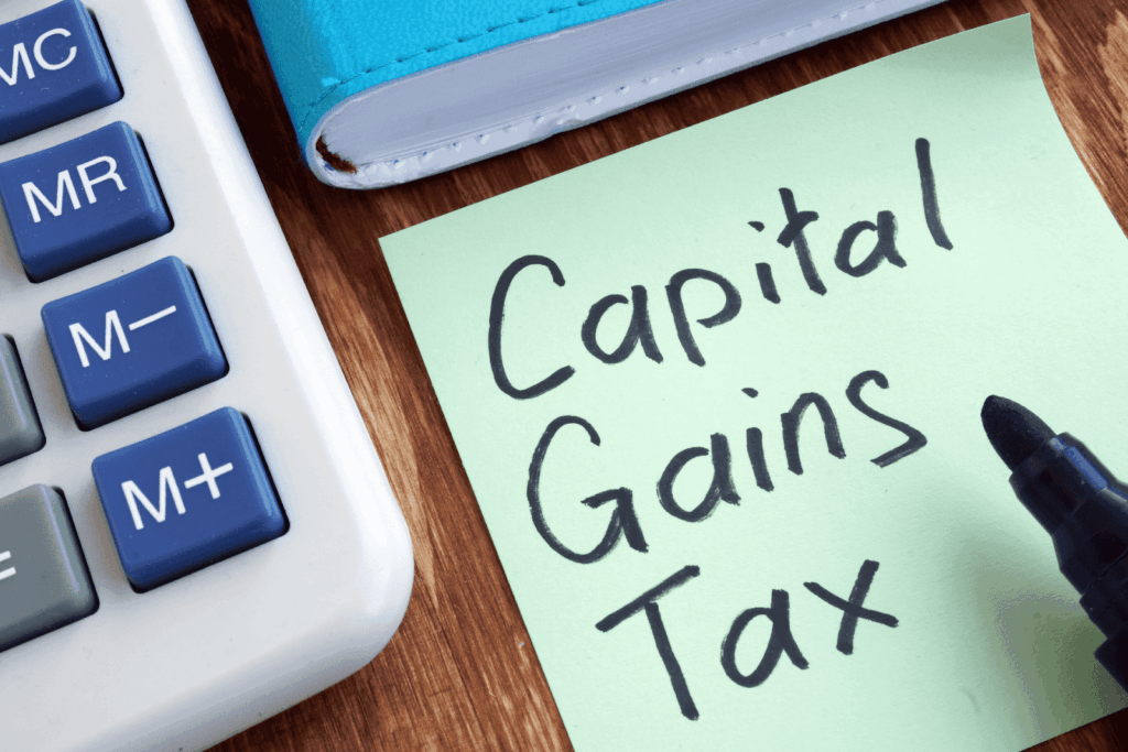 Sticky note with Capital Gains Tax written beside calculator and notebook.