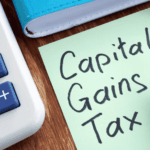 Sticky note with Capital Gains Tax written beside calculator and notebook.