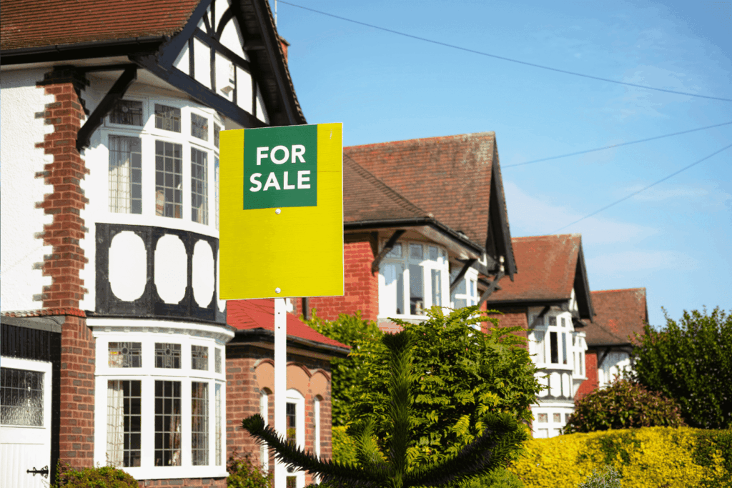 Yellow and green For Sale sign in front of traditional brick houses