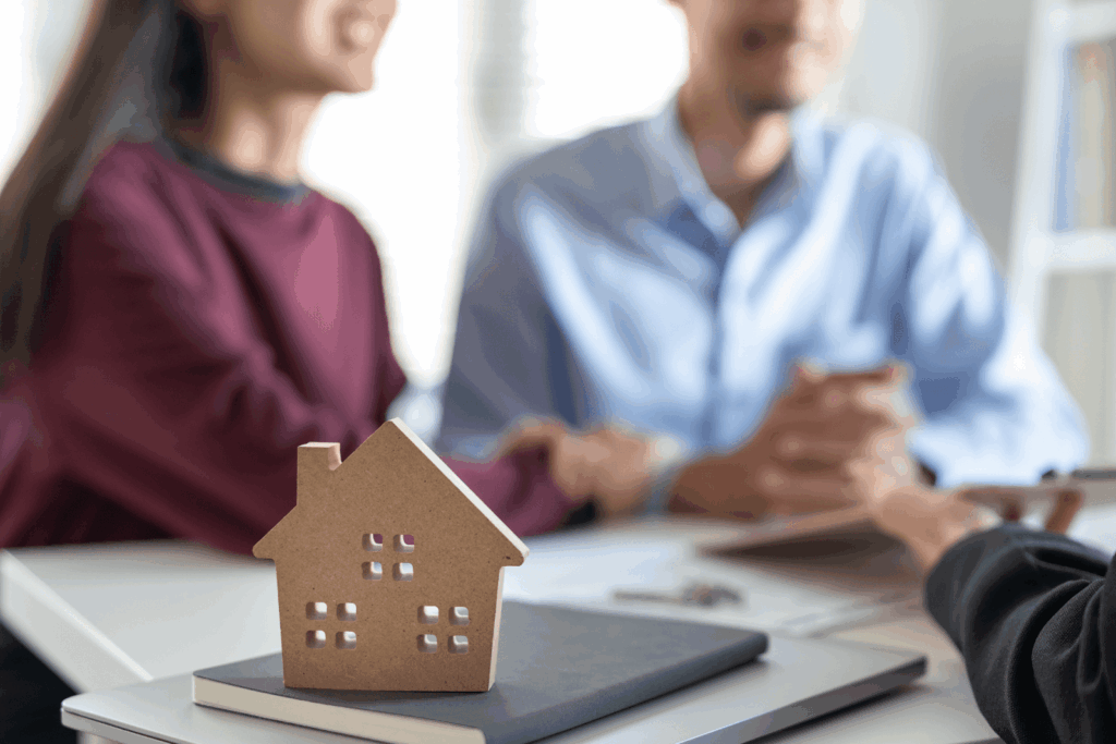 Couple meeting with advisor at desk with small wooden house model.