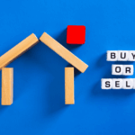 Buy or sell concept using wooden house blocks on blue surface.