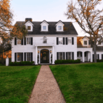 Large two-story white brick house with black shutters and spacious front lawn.