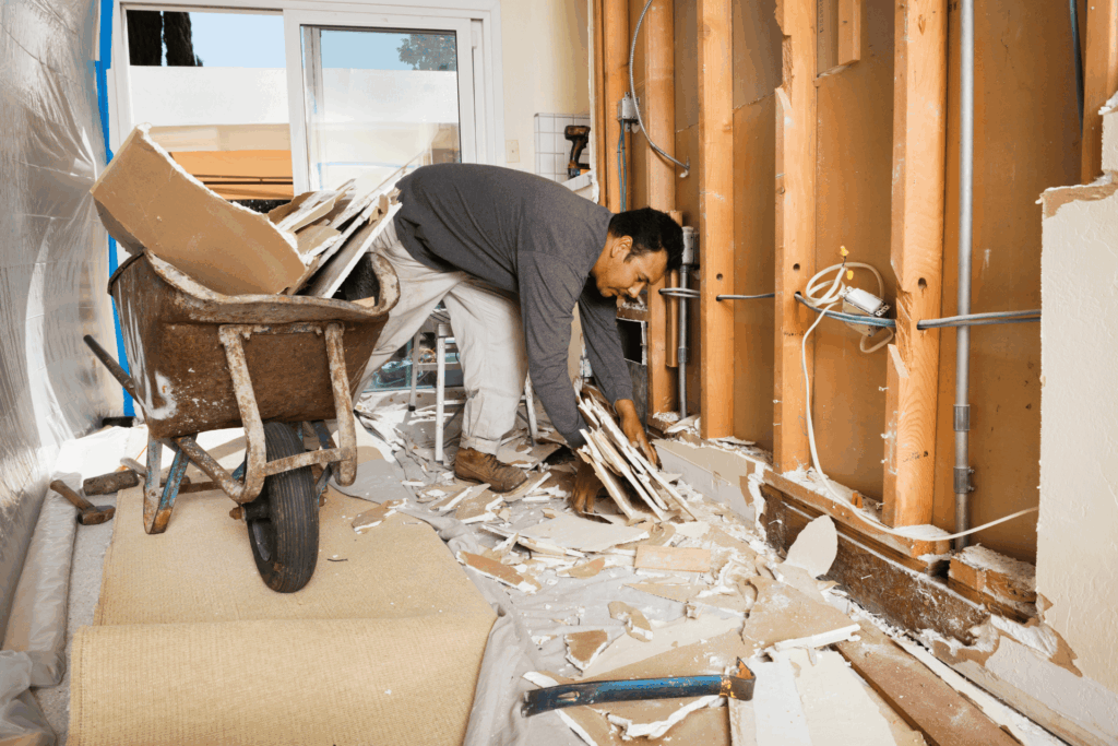 Worker clearing debris inside a damaged home, illustrating Deceased Estate Clean Up Services.