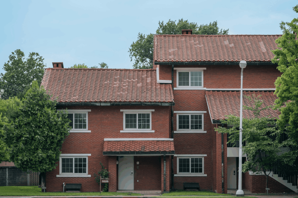 Vacant house for sale shown as a brick home with tile roofing and an empty front yard.