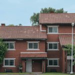 Vacant house for sale shown as a brick home with tile roofing and an empty front yard.